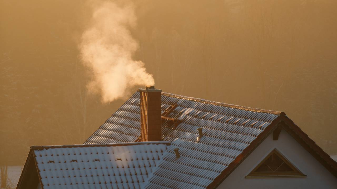 Smoke coming out of the house's chimney in wintertime