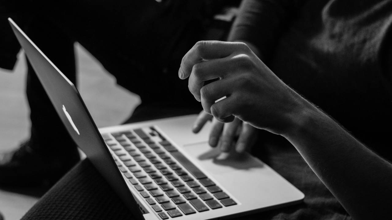 A black & white photo of a person using a laptop 